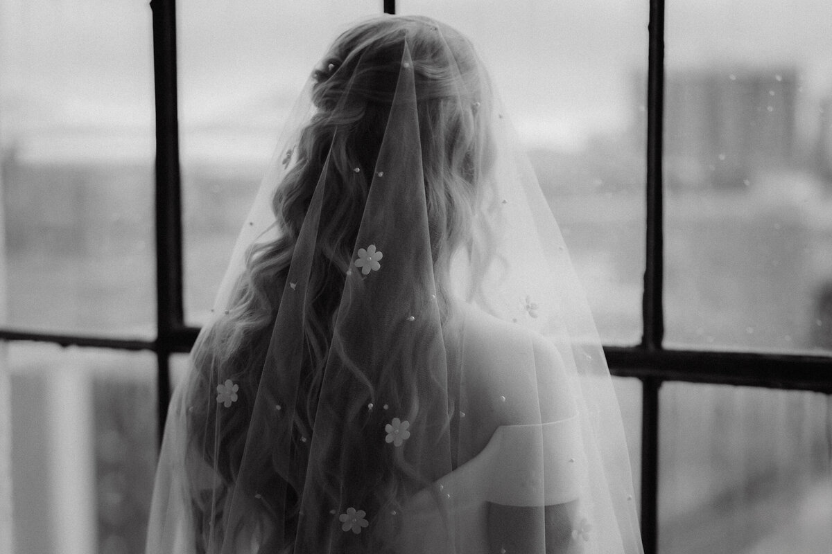 Portrait poétique d’une mariée de dos, voilée et baignée de lumière naturelle au Studio Giovanelli à Montréal, capturé dans un style moody par Jeff Gagnon photographe.
