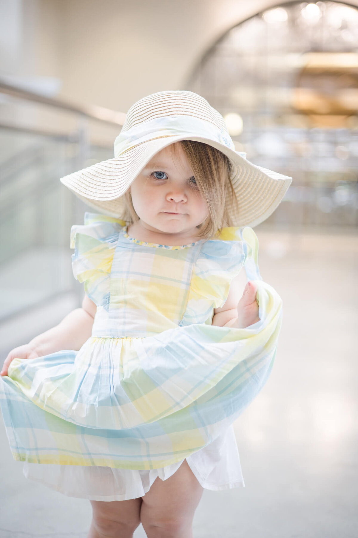 happy toddler girl glaring while holding her dress on a bridge