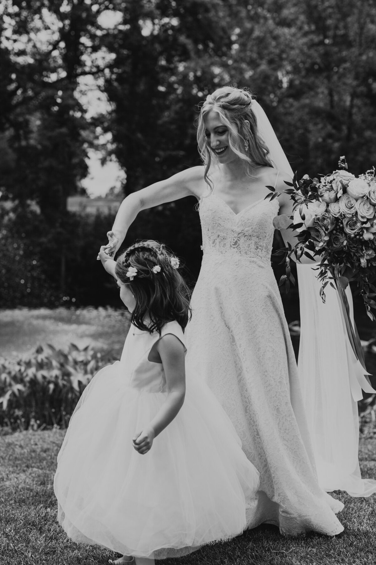 black and white portrait of bride and flower gril dancing twirling flower girl flower crown