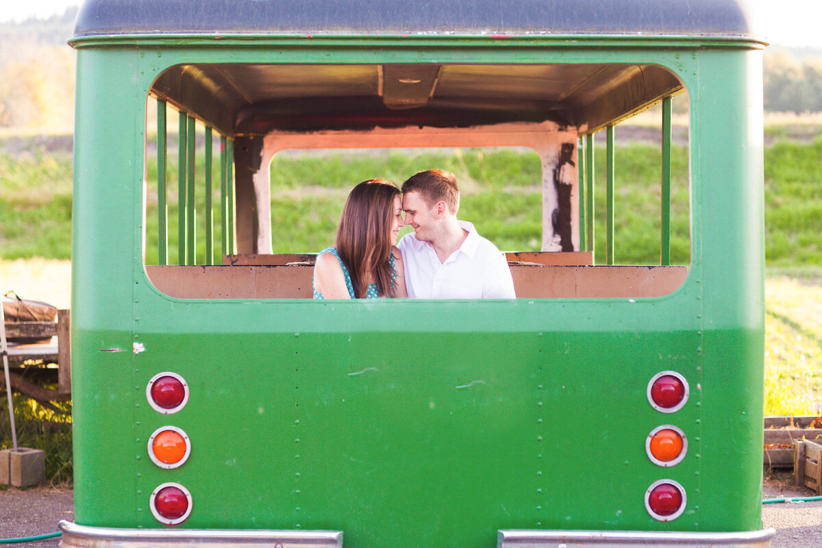 engaged couple putting their heads together in old, green bus