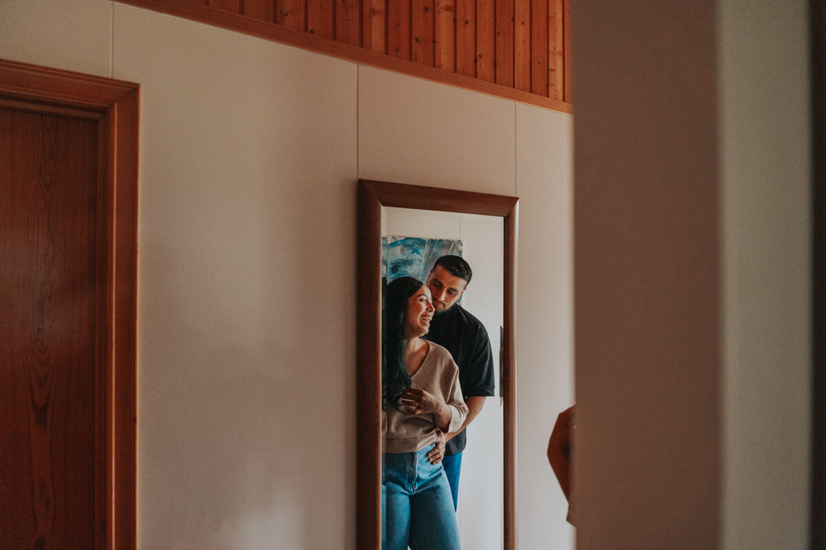 Couple stands in front of a mirror embracing 