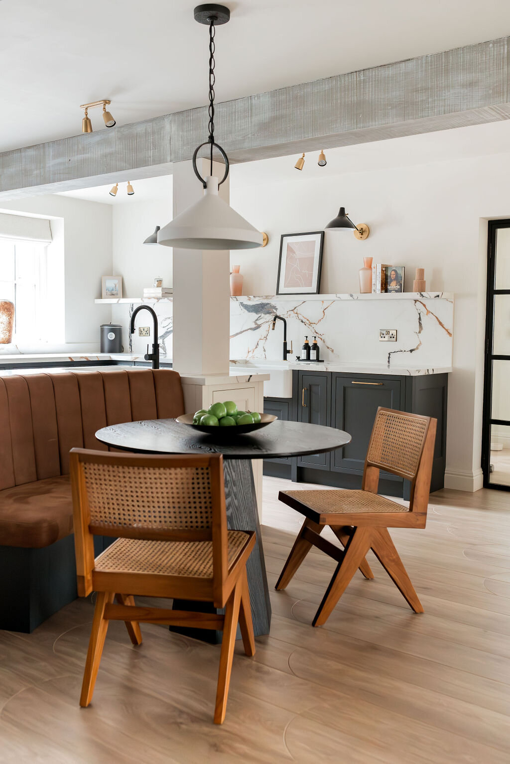 A modern kitchen with a built-in seating area with two wooden chairs and a small table.