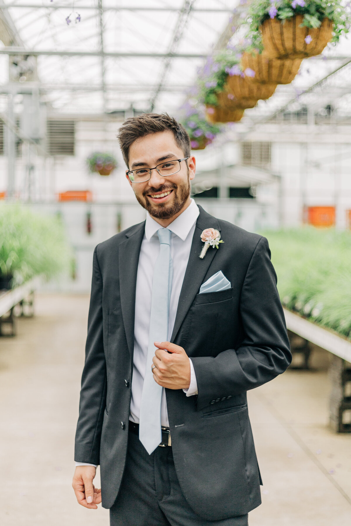 groom smiling at camera in greenhouse