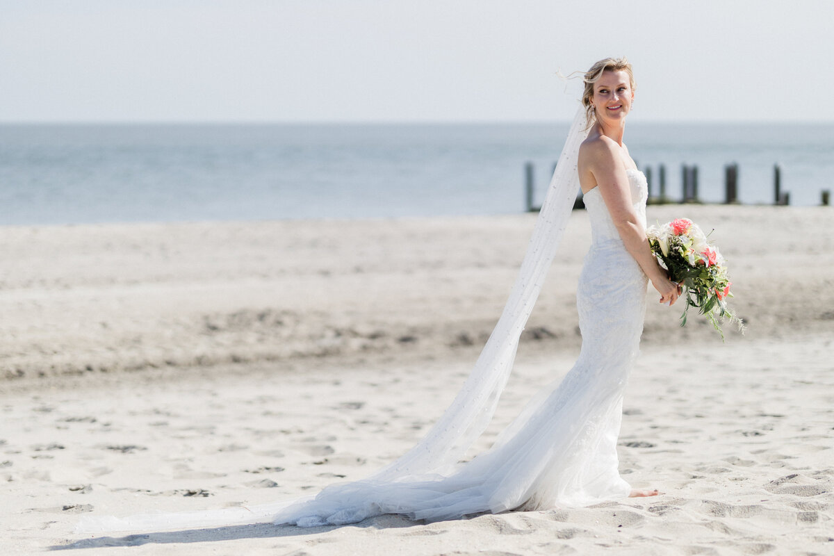Bride walking on the sand with a rosy and green boutique as she wears her wedding gown