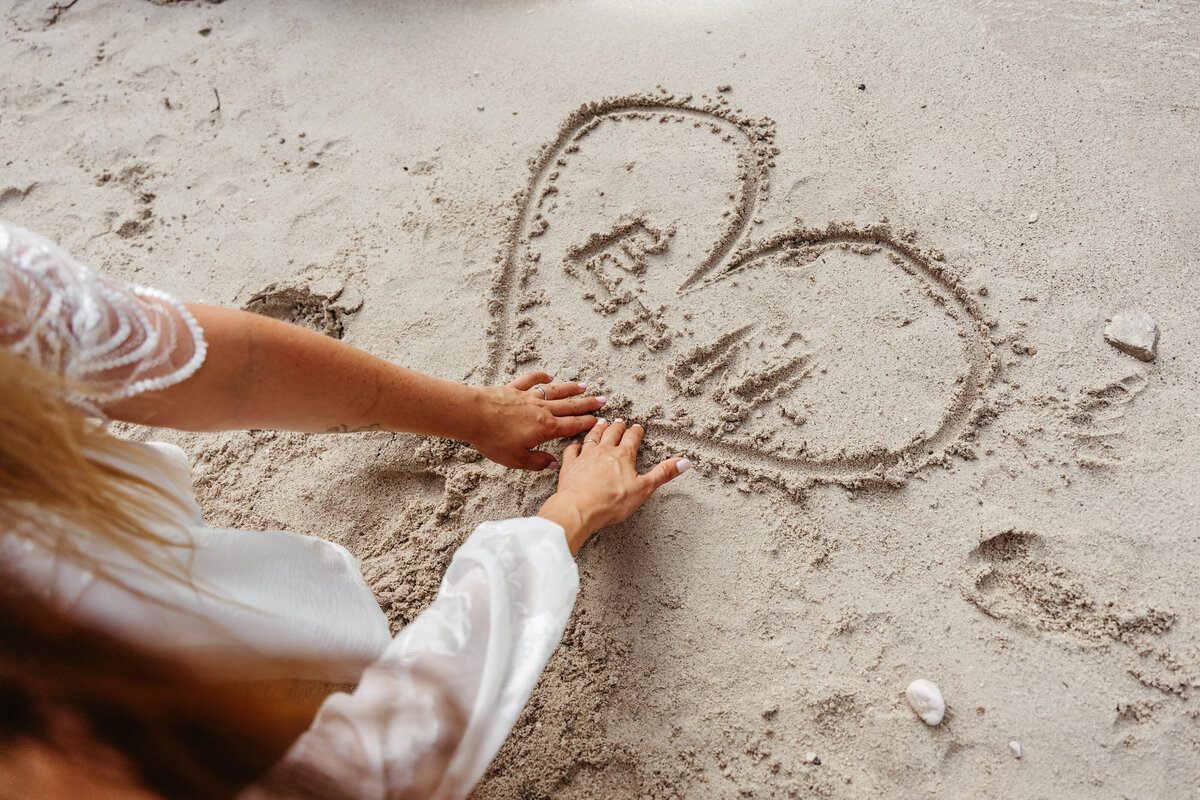 romantic couple drawing heart in sand Soča Valley