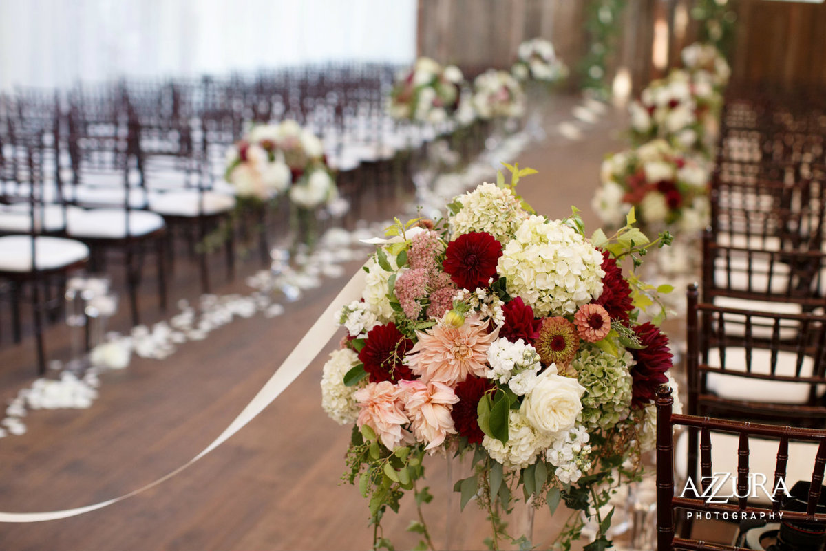 fall ceremony aisle with large arrangements of antique hydrangea, red and white dahlias, zinnias, blush roses, and greenery at Sodo Park Seattle