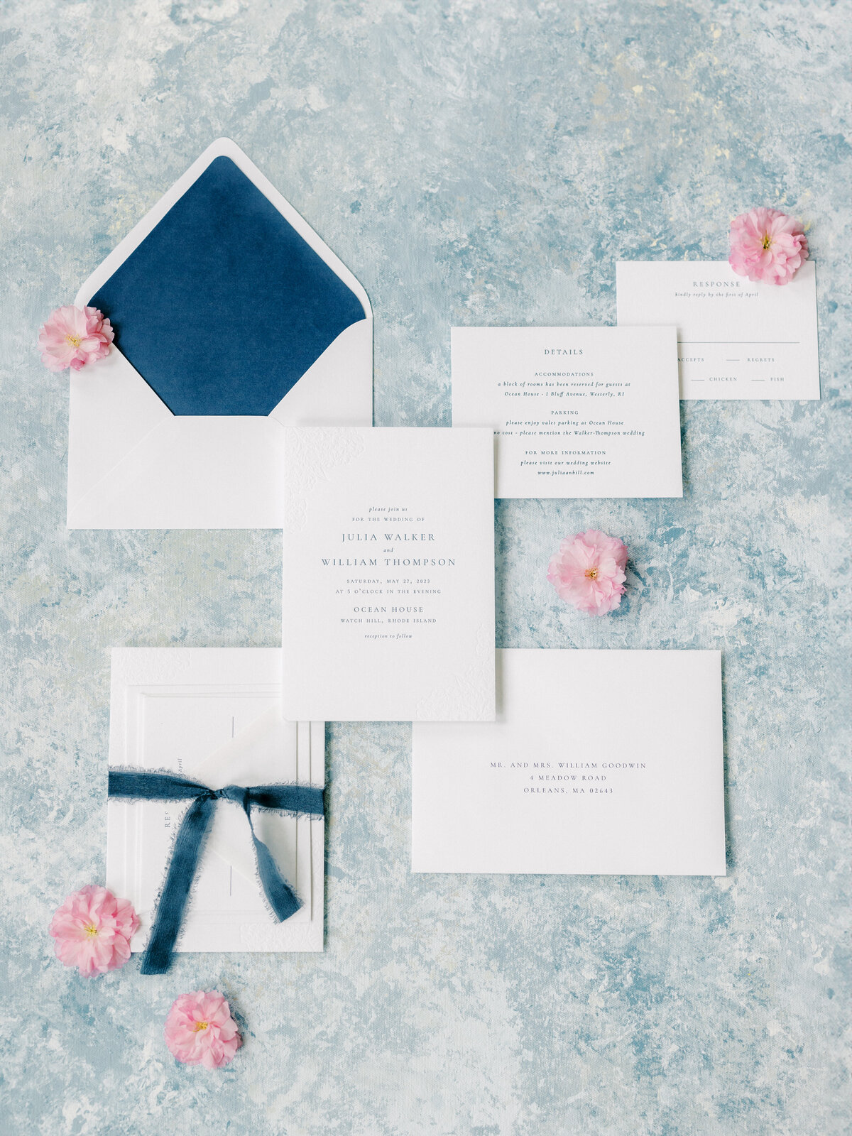Flat lay on a blue and white fine art wedding invitation suite on a blue background