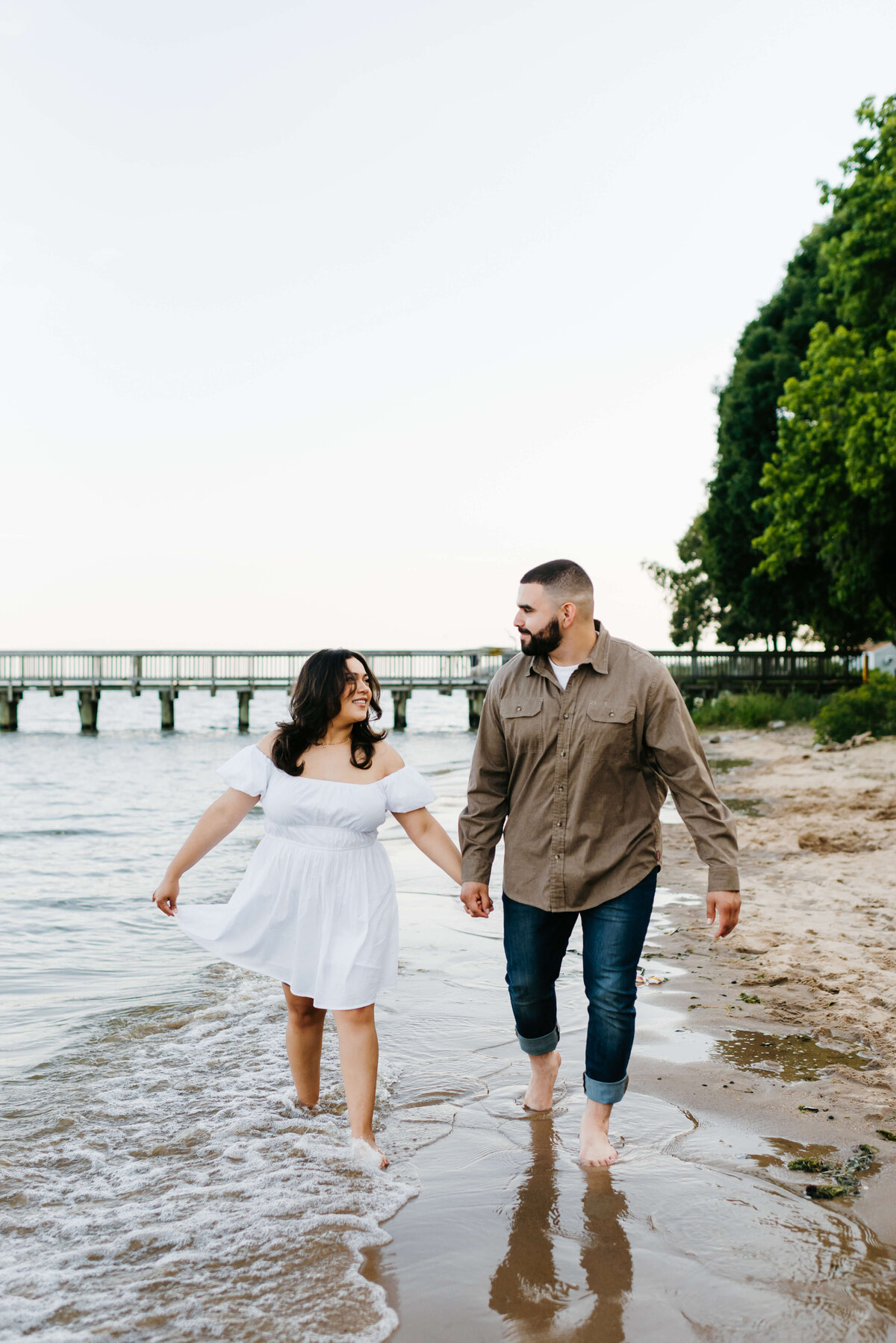 beach engagement photo at a lake in Virginia with couple holdin ghands and running in the water together