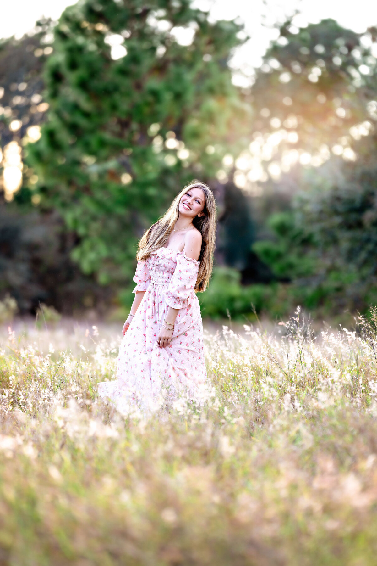 Golden hour glow on senior girl sitting in a field in Windermere, Florida