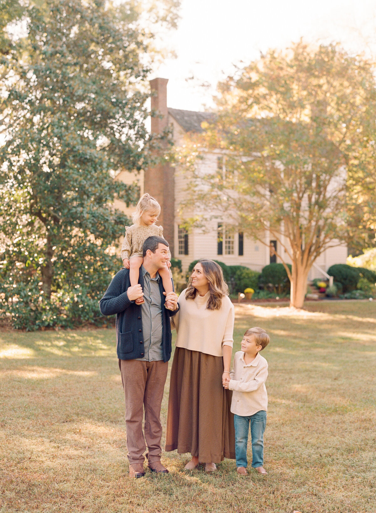 Family walks through a park in Wake Forest for family photos. Family walking during their family portrait session in Wake Forest, NC. Photographed by Raleigh family photographer A.J. Dunlap Photography.