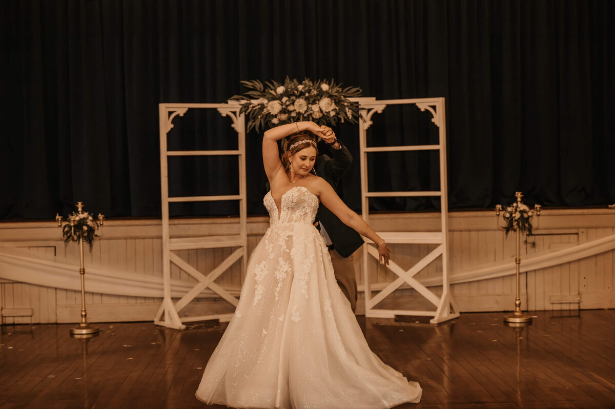 A bride and groom share a romantic dance in the center of a beautifully decorated room, surrounded by soft lighting - photo by Jamie Simmons