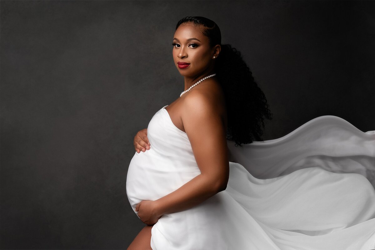 Pregnancy portrait in west palm beach maternity studio with white fabric on a fine art backdrop.