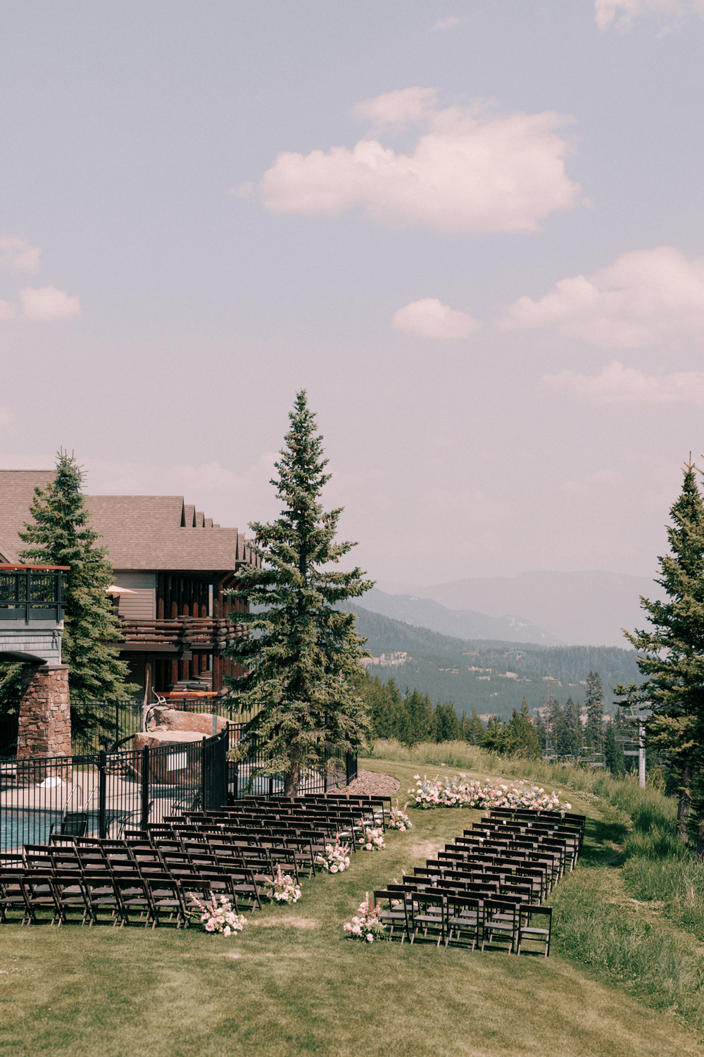 Outdoor ceremony setup for a summer wedding at Moonlight Basin, with dark wood chairs and pastel floral arrangements overlooking the Montana mountains.