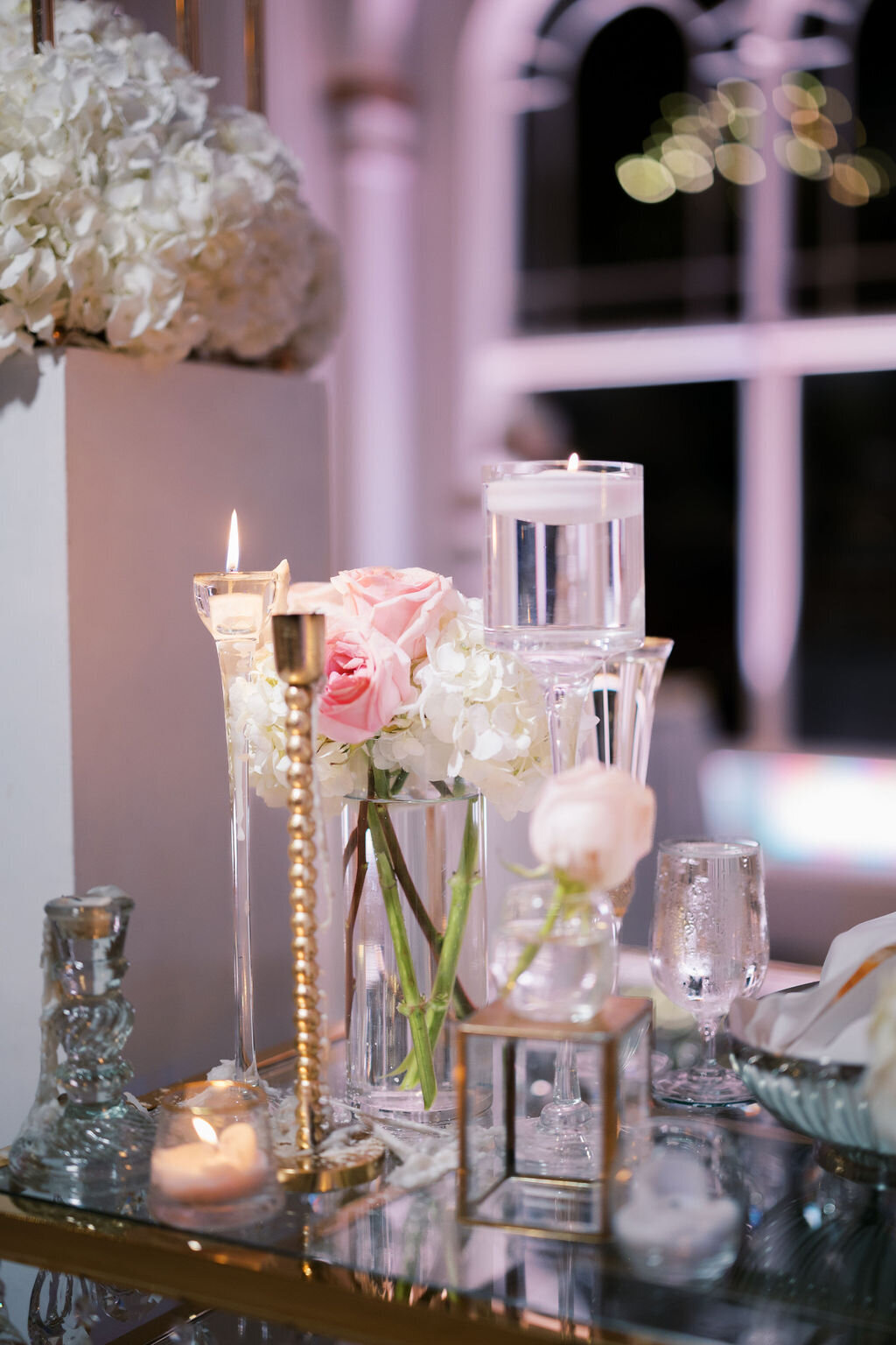 glass candles and pink and white roses on a table