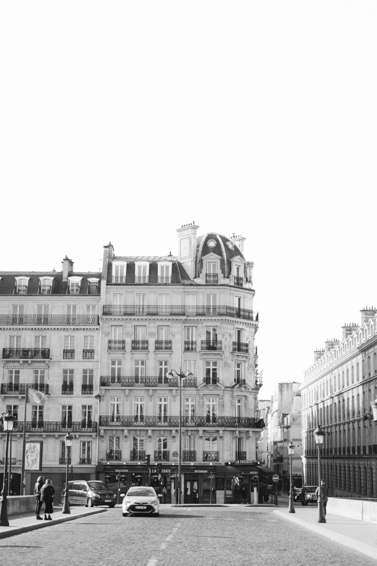 Black and white photograph of classic Parisian-style buildings with ornate balconies, capturing the timeless elegance and architectural charm of a European city.