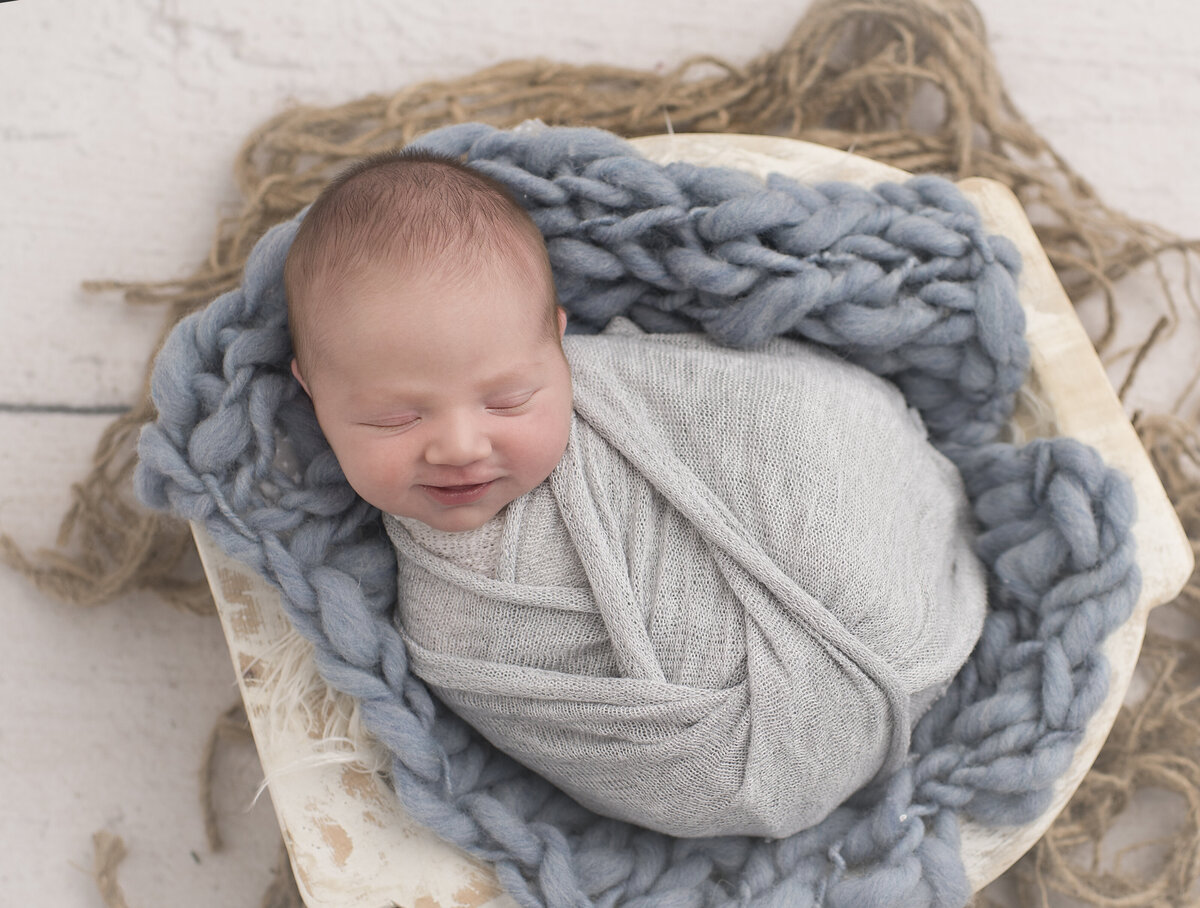 baby boy wrapped with blankets and a backdrop indoors