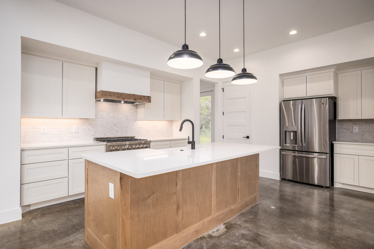 concrete floors in kitchen with wood island and white countertops