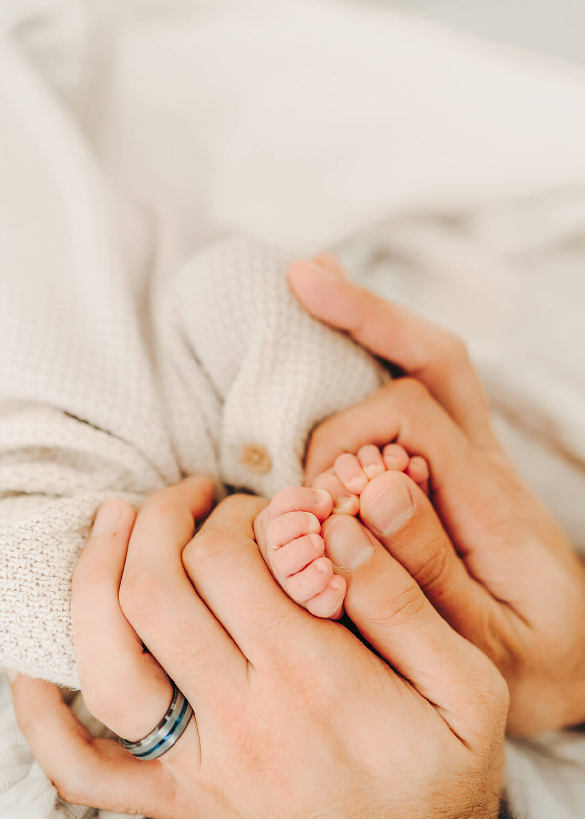 detail photo of newborn baby's feet in dad's hands