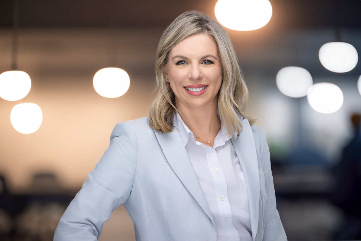 Explore this professional portrait of a confident Caucasian businesswoman, set against a modern, softly-lit background. She wears a light blue blazer and white blouse, exuding poise and professionalism. Perfect for personal branding and corporate headshots in Cincinnati, this image reflects the expertise of our Cincinnati-based portrait photography studio.