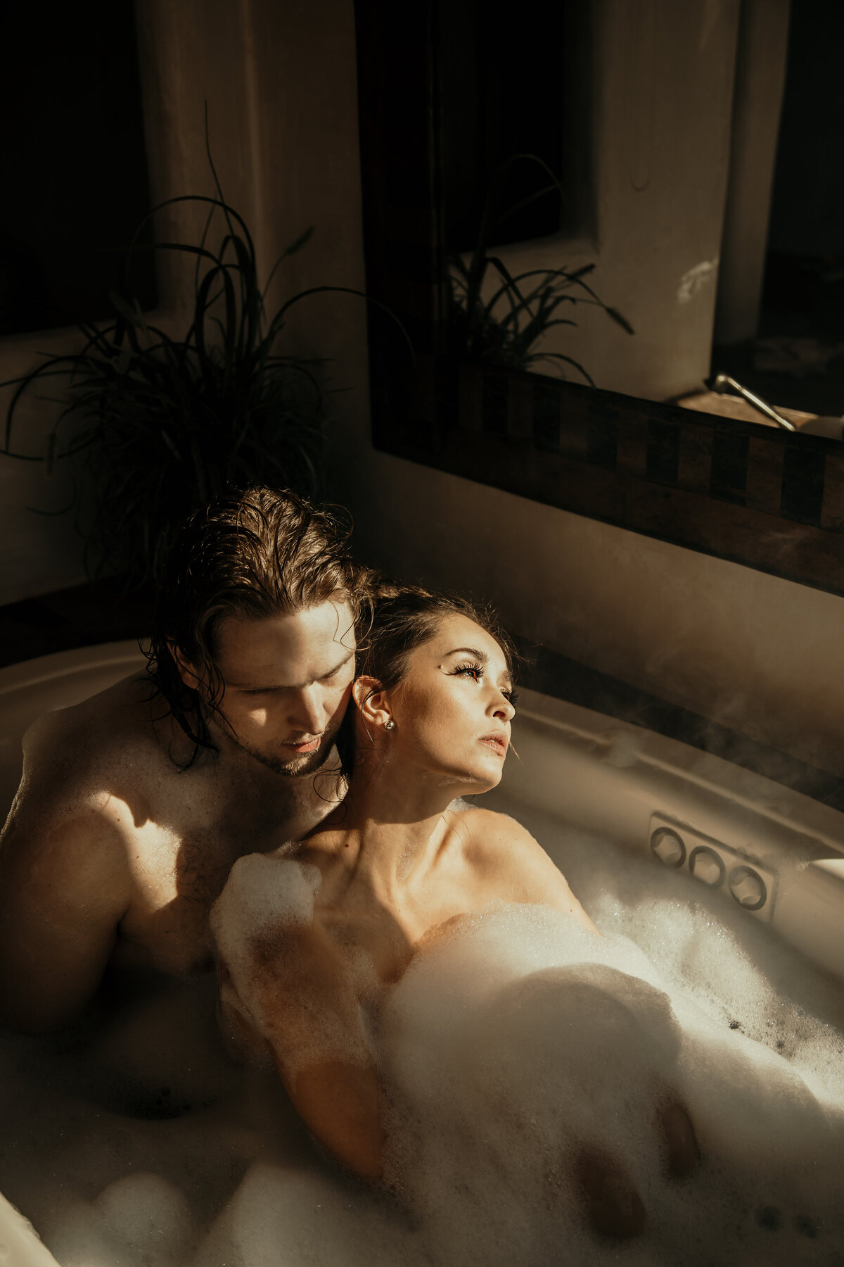 a couples is sitting in the bathtub with bubbles and rays of sunshine flooding in