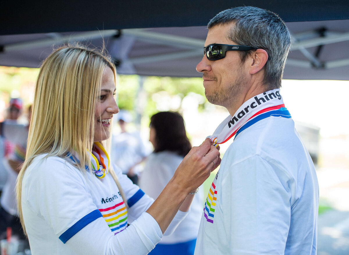 Ottawa event photography showing a male and female putting on pride handkerchiefs and t-shirts.  Captured by JEMMAN Photography COMMERCIAL