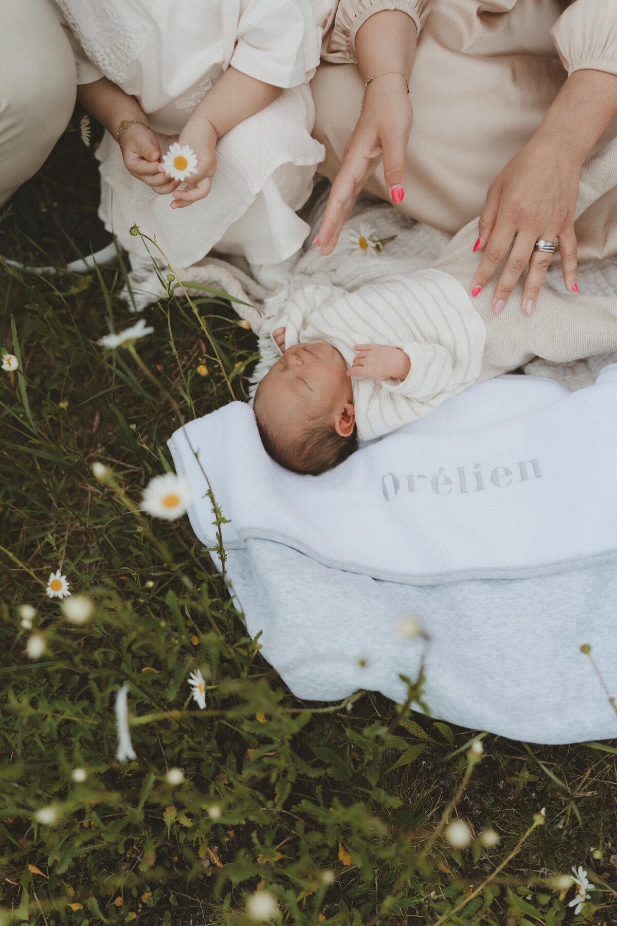 Foto van een newborn baby buiten tussen de bloemen op een dekentje.