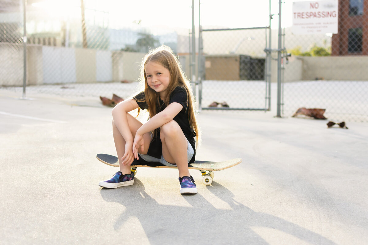 Girl sitting on a skateboard on a parking garage