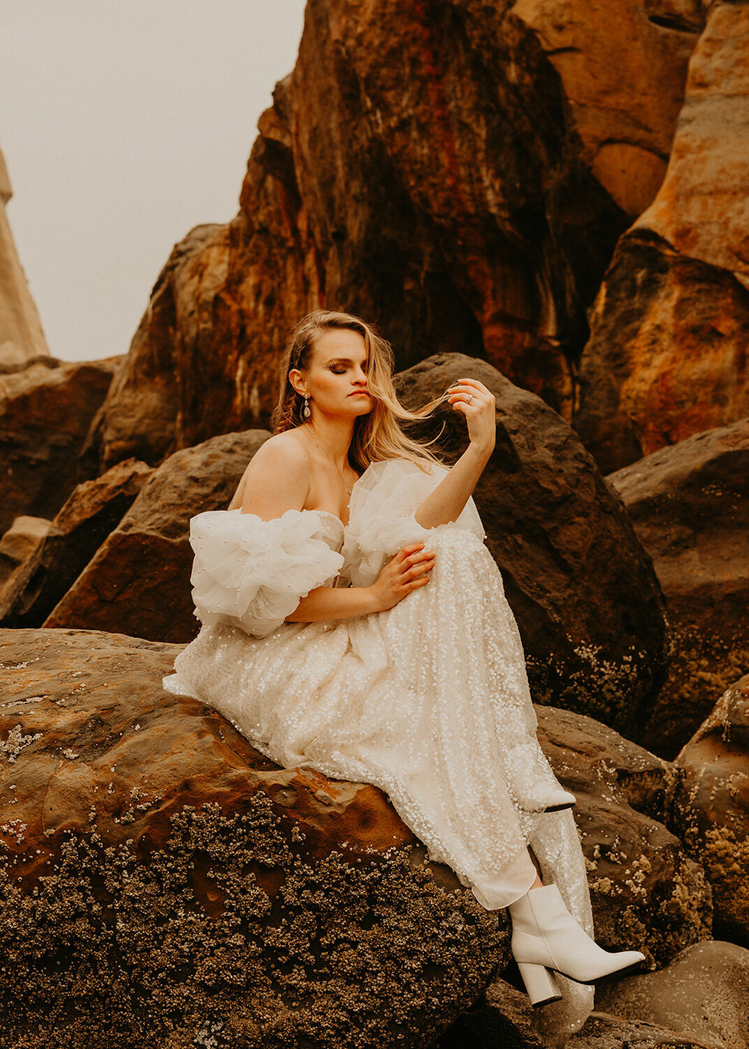 Bride sitting down on a rock while wearing her white wedding gown