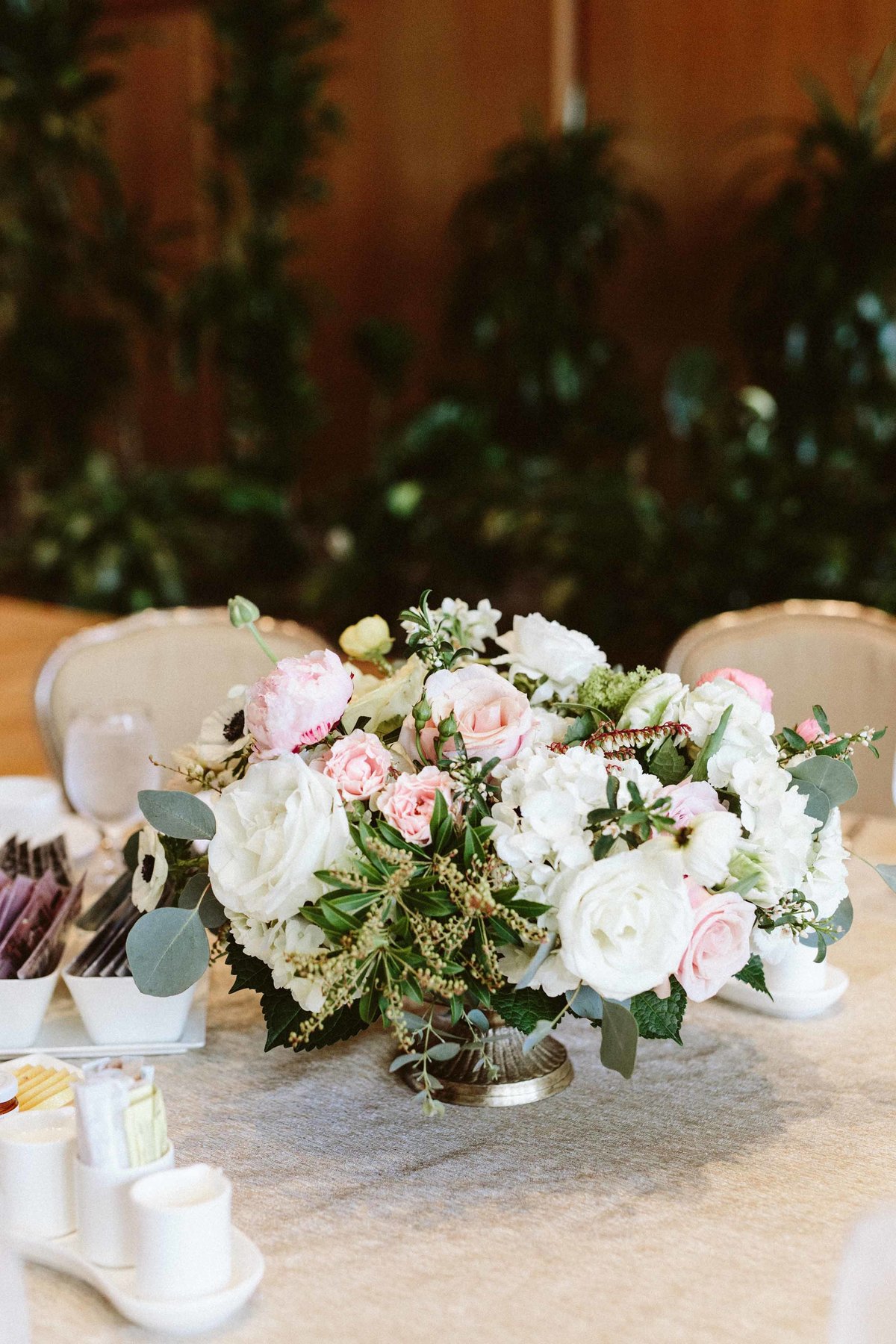 centerpiece for baby girls birthday party of pink roses, white hydrangea, and greenery in silver compote