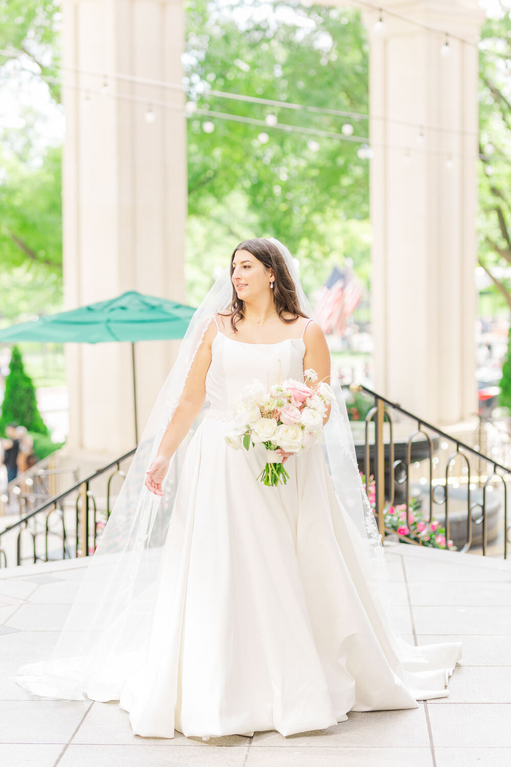 Bride holding bouquet with veil outside wedding venue