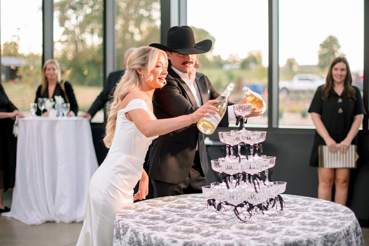 A couple pouring a champagne tower in the greenhouse