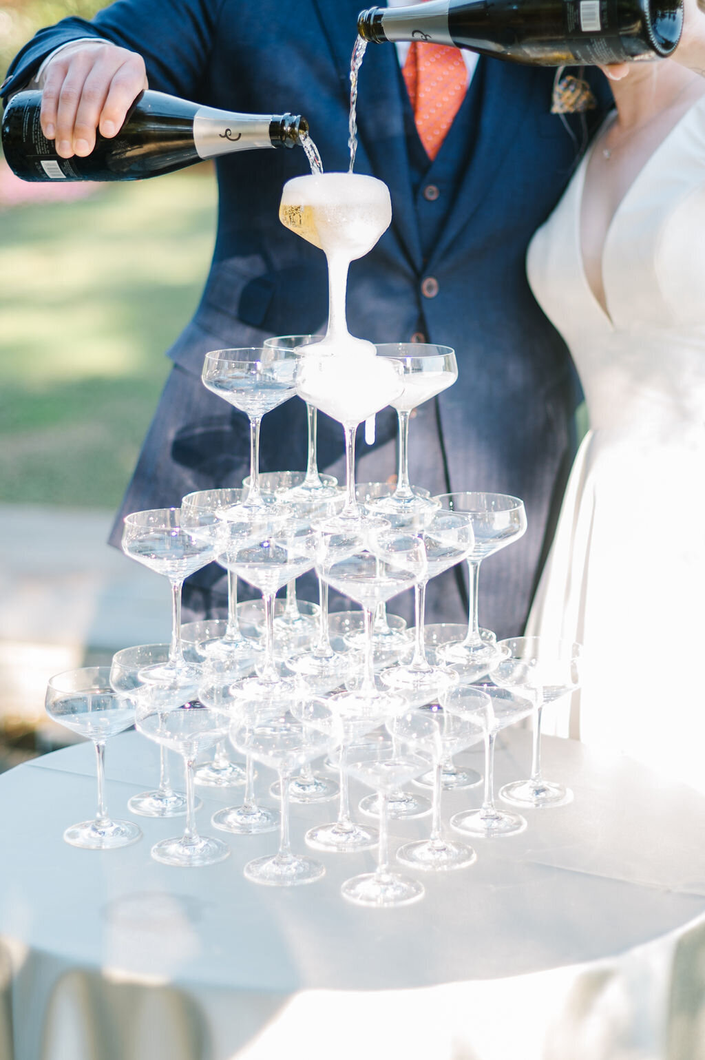 Wine glass tower with wine being poured by the couple