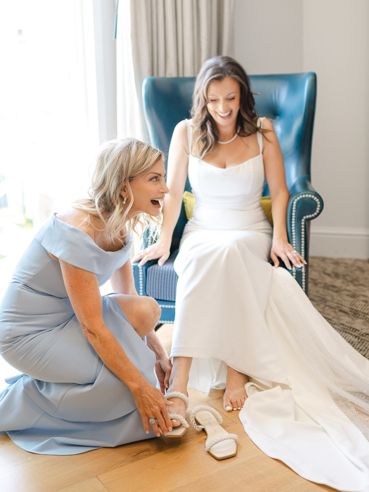 Mother of the bride helps her daughter put on pearl-embellished wedding shoes at Lido House, Newport Beach