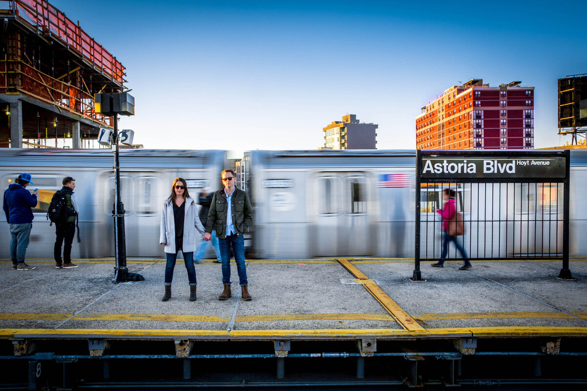 Image of a couple standing on a subway platform from the other side.