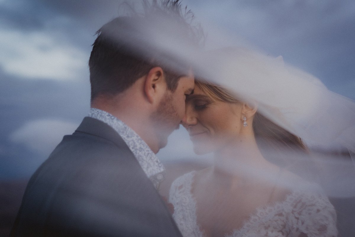 Bride and groom closeup underneath bridal veil