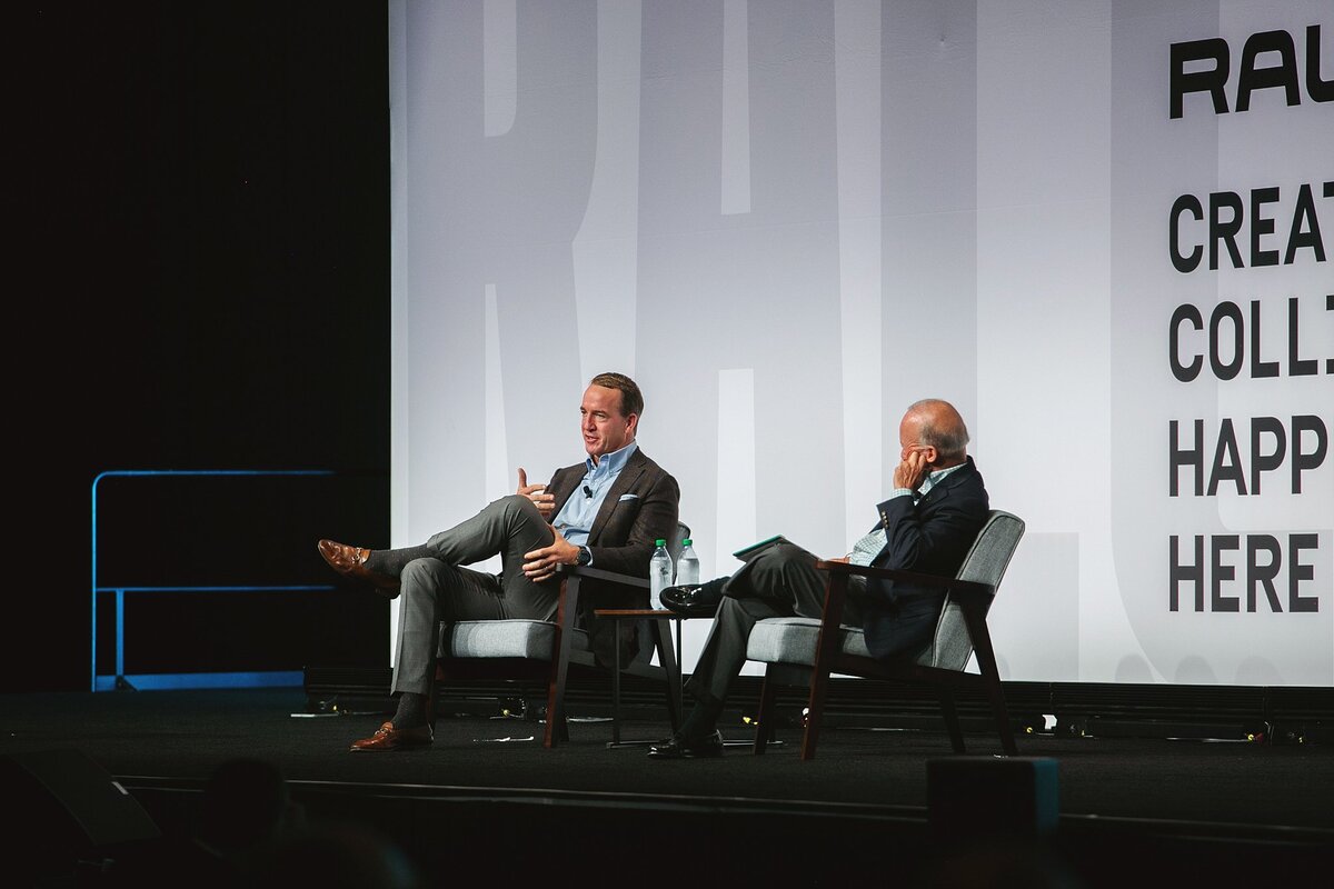 two-business-leaders-engaged-in-a-fireside-chat-on-stage-at-the-rally-conference-in-indianapolis-discussing-insights-with-a-live-audience