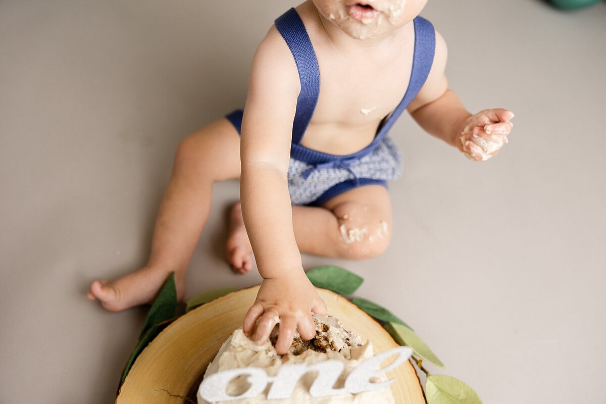 detail of baby boy's hand grabbing birthday cake