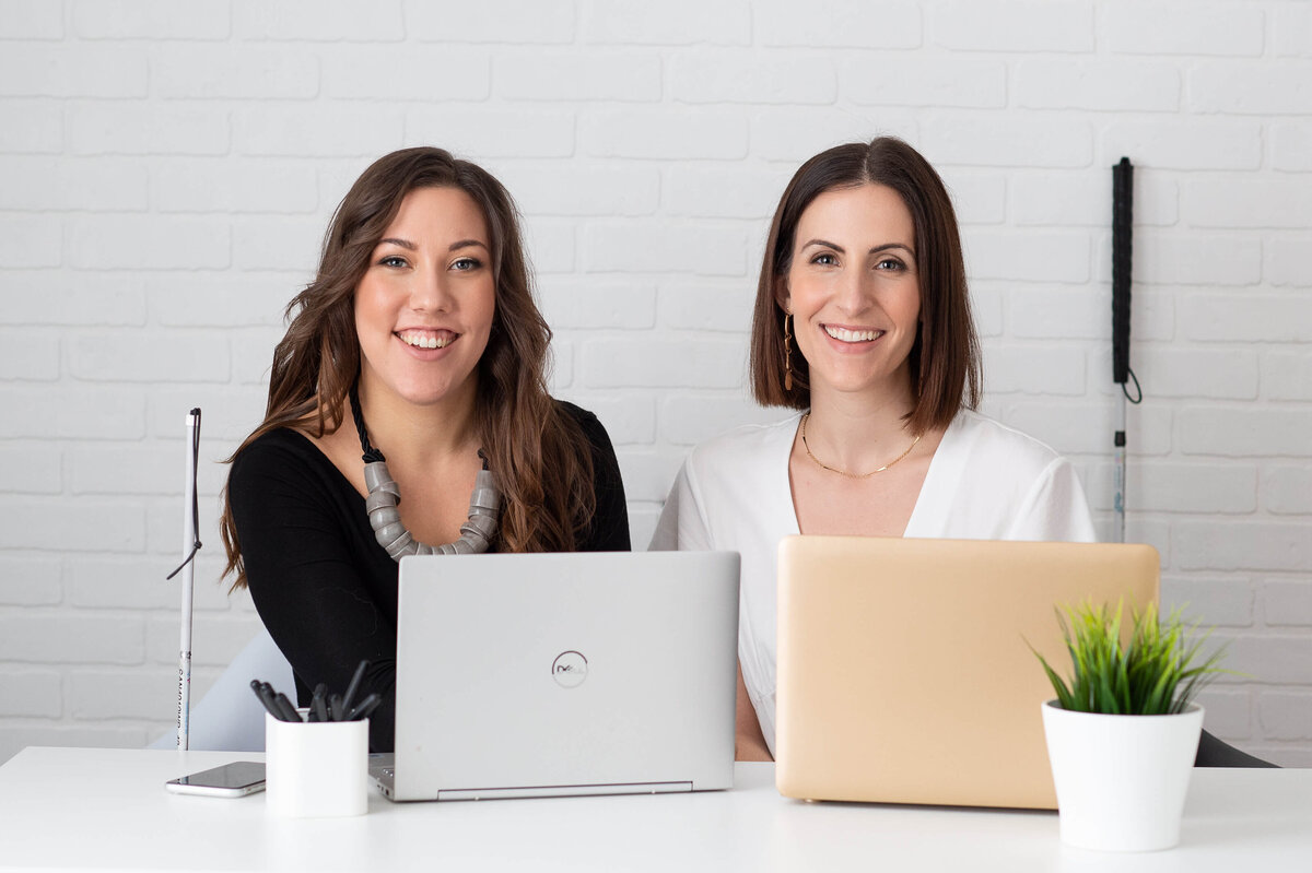 Ottawa brand photo of a team of two female consultants sitting at a desk with their laptops working together