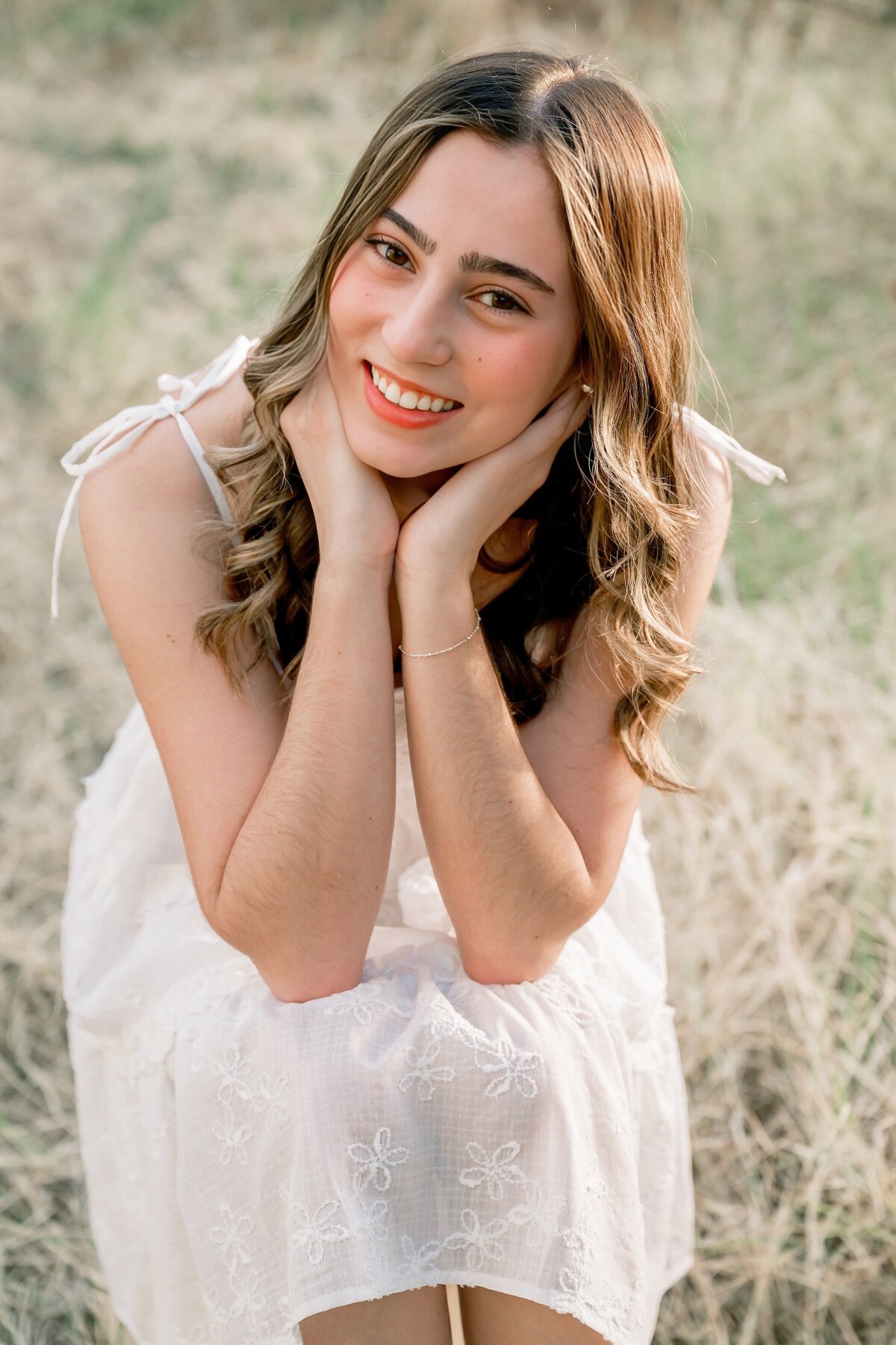 senior girl smiling at camera in the grassy field
