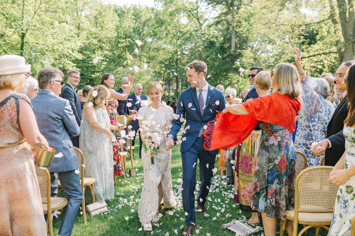 A happy couple recesses down the wedding aisle after being pronounced  married. Their friends and family throw confetti at them.