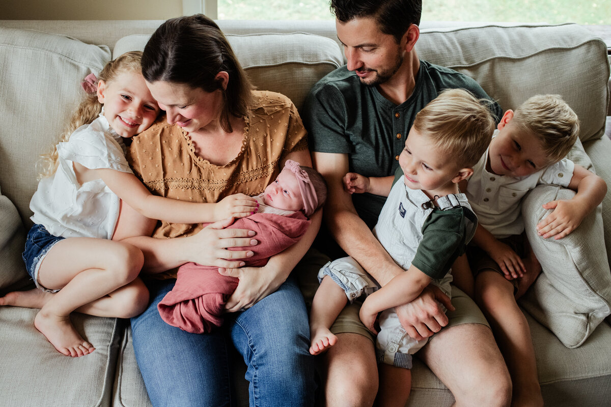 family cuddling together for newborn photos at home