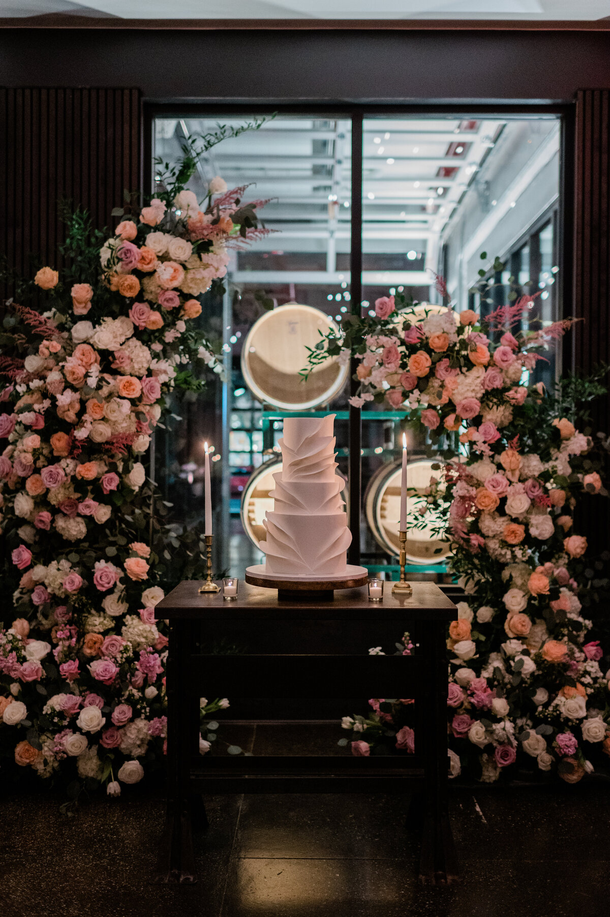 Wedding cake sits in between two flower arches 