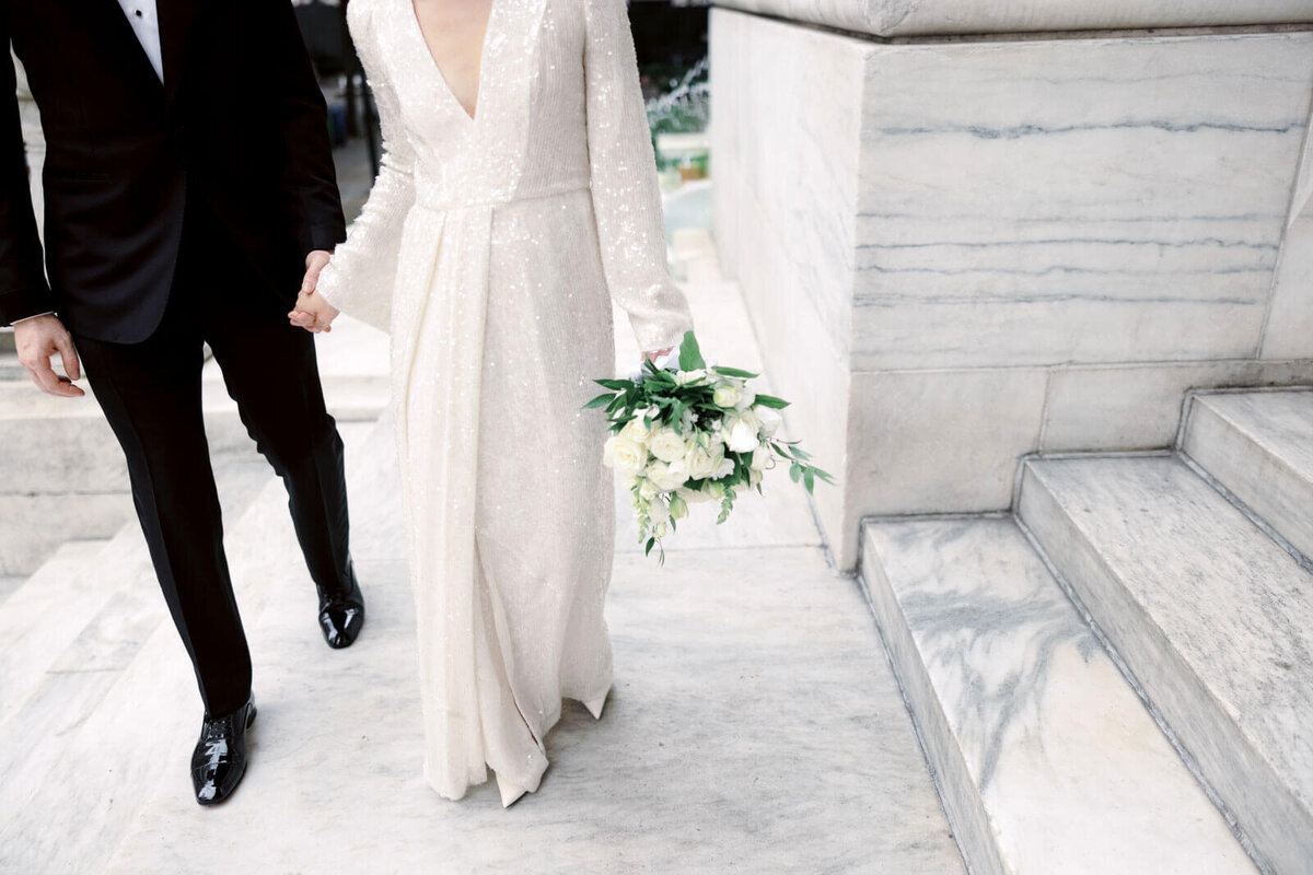 Lower half-body shot of the bride and the groom walking in the New York Public Library's entrance. Image by Jenny Fu Studio