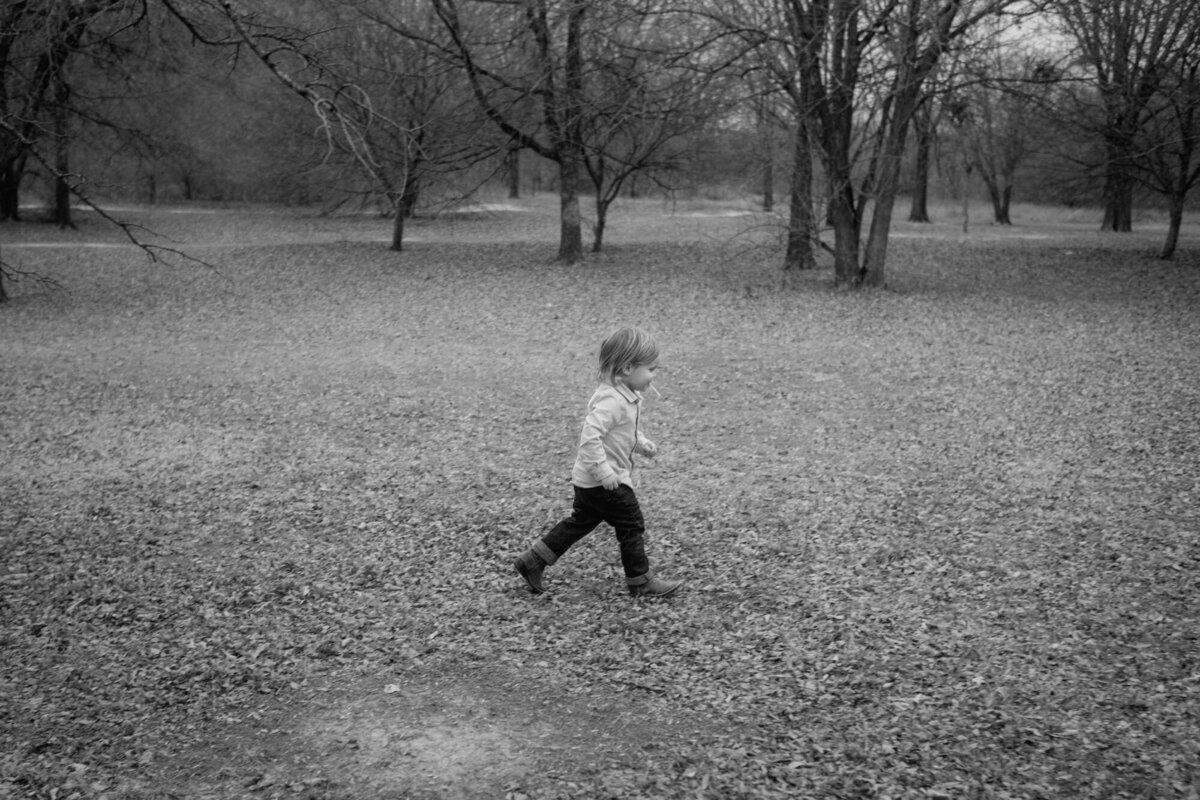 Young boy runs over a grasfield.