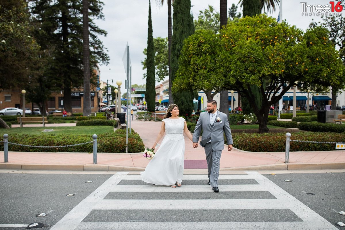 Bride and Groom cross the street at City of Orange's Downtown Circle area with famous water fountain