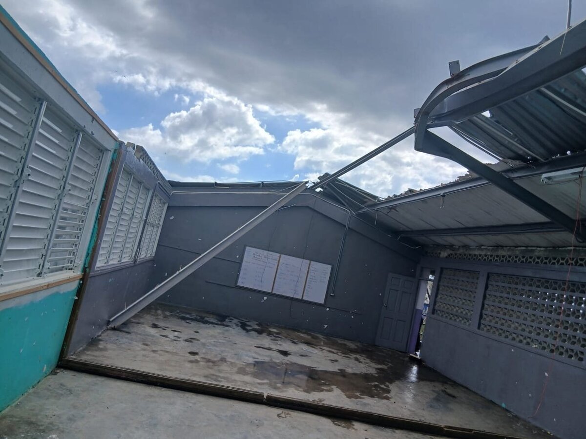Collapsed metal roofing and debris scattered across the schoolyard after Hurricane Melissa.