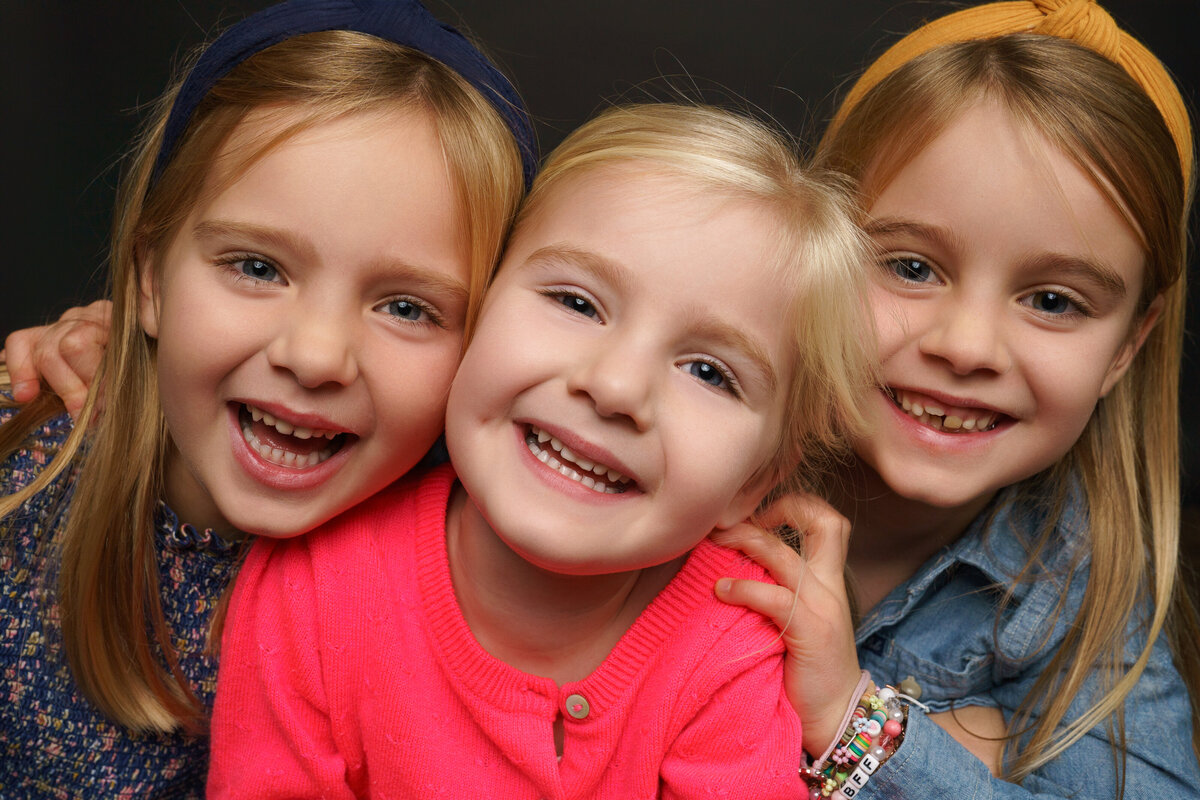 Extreme Closeup portrait of 3 sisters smiling and laughing at camera