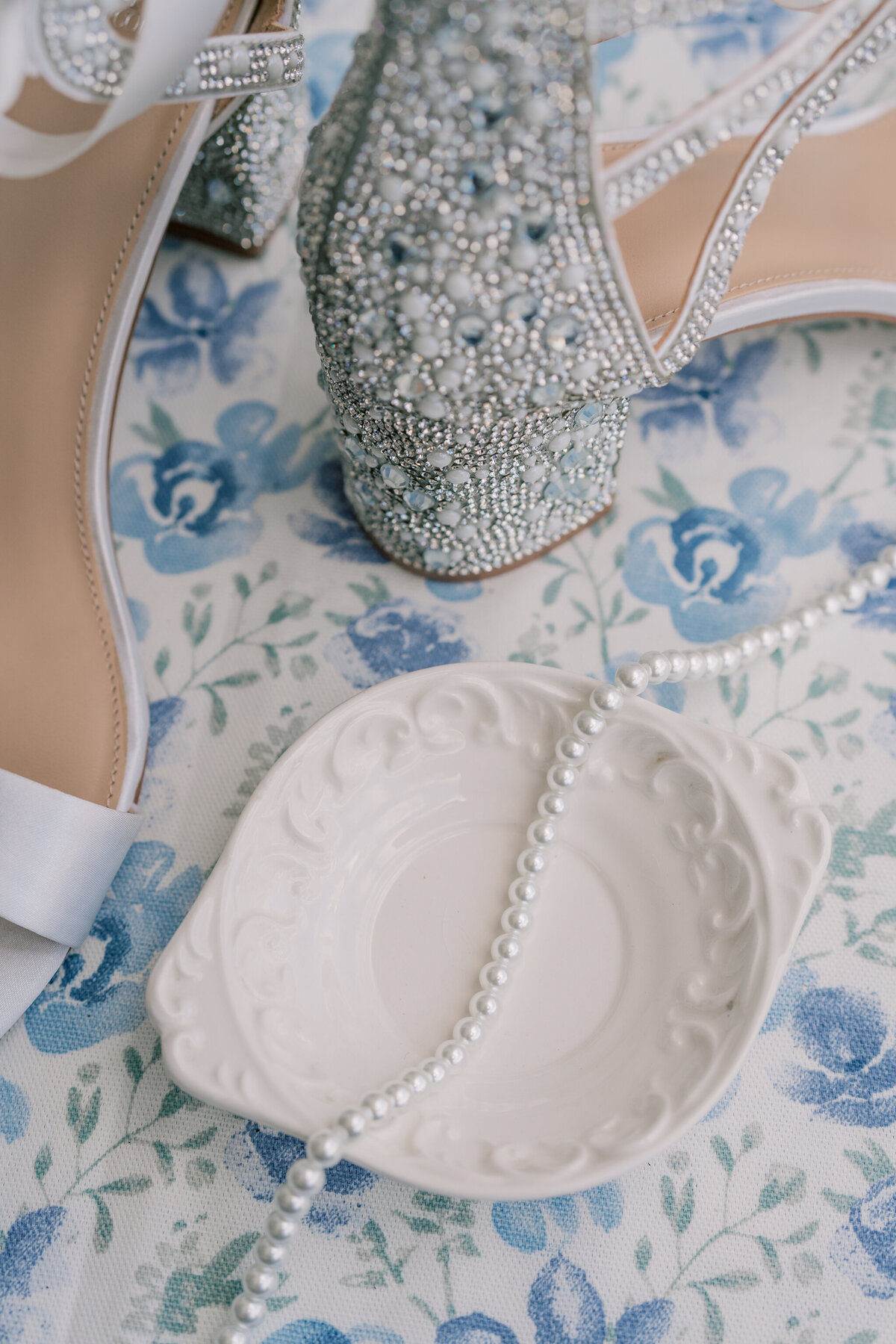 Weddings in Spain | A white vintage dish, in front of a pair of silver rhinestone covered heels, holds a pearl necklace. Captured in Galicia, Spain by Luxury Destination Wedding Photographer, Caitlin Wilcox.