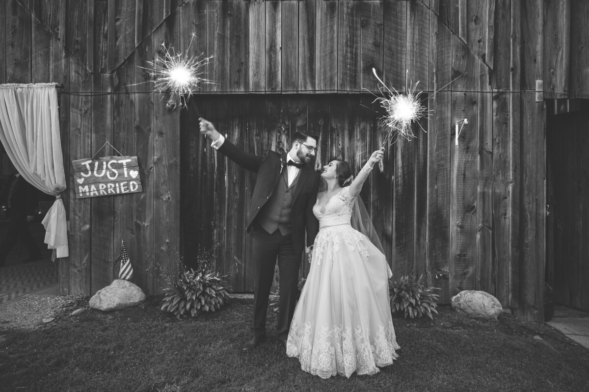 Bride and groom holding sparklers by just married sign.