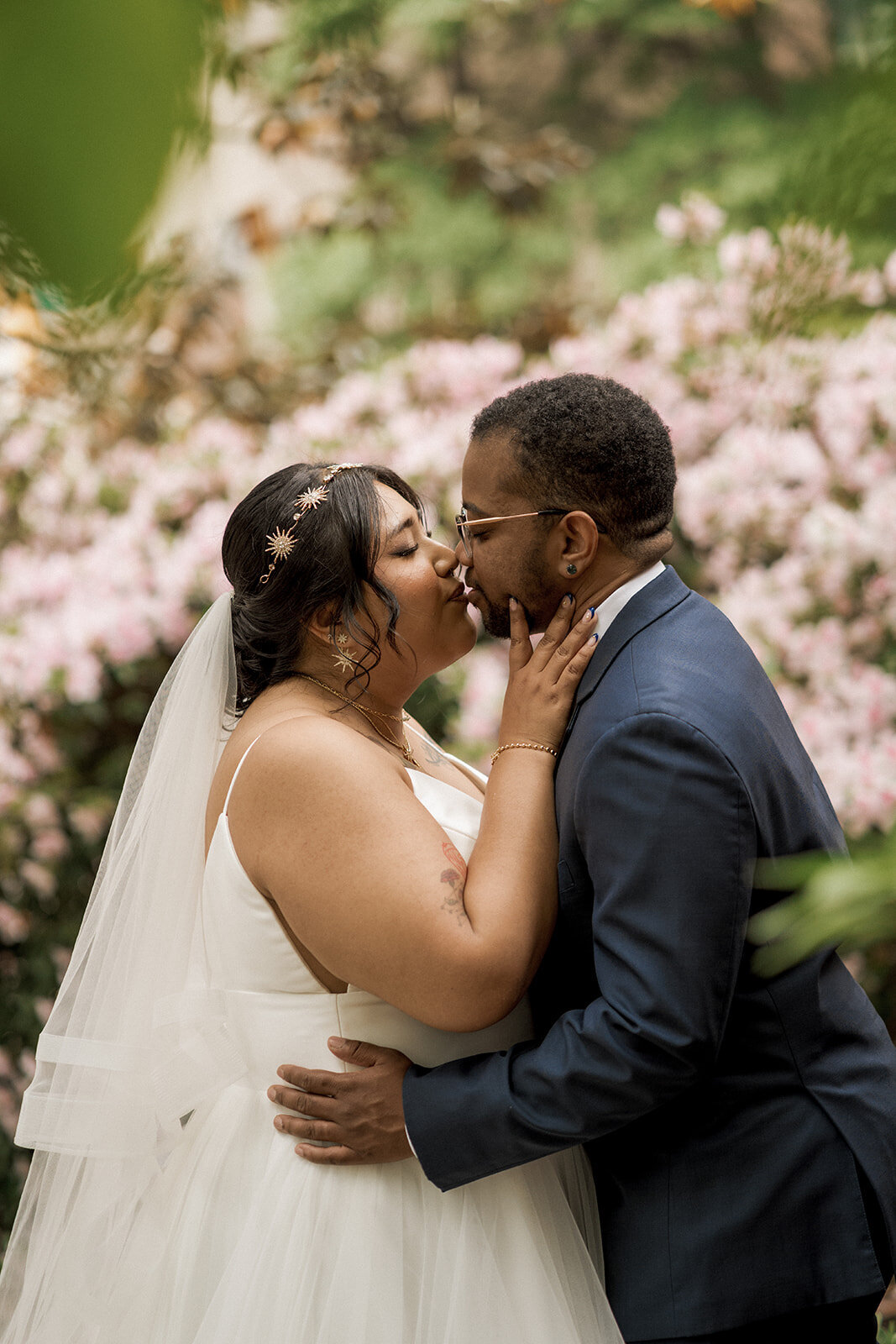 spouses about to kiss on wedding day in park with flowers